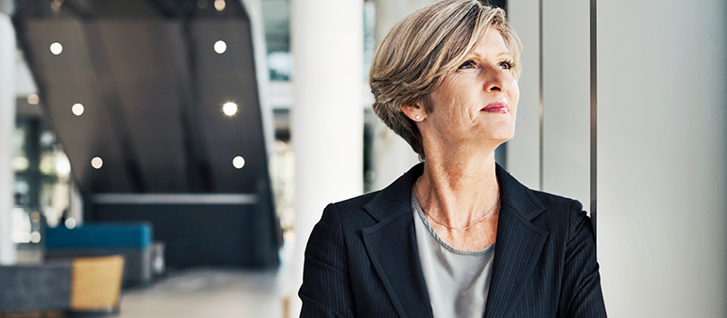 Businesswoman cheerfully looks out of the window at her place of work.