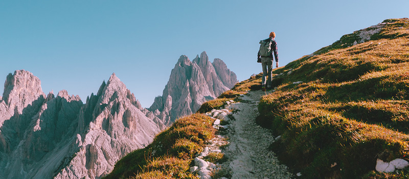Hiker traversing rocky terrain as they venture up a mountain.