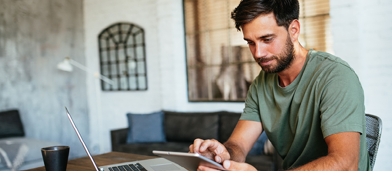 Man using digital tablet at home, while working