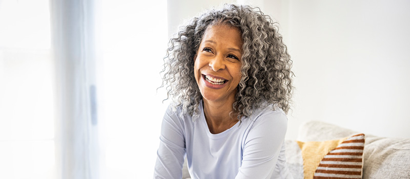 Woman sitting at home on couch, smiling