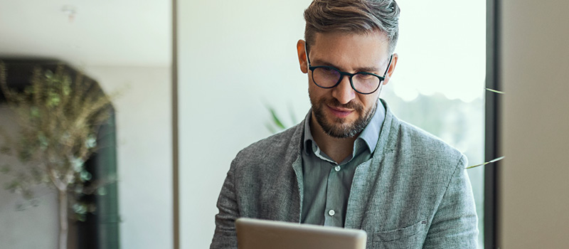 Businessman in office drinking coffee and looking at tablet.