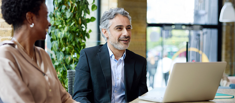 Woman talking animatedly with her male work colleague in a light, airy office.