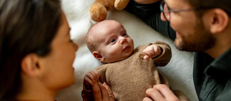A mother and father looking fondly at their newborn baby.