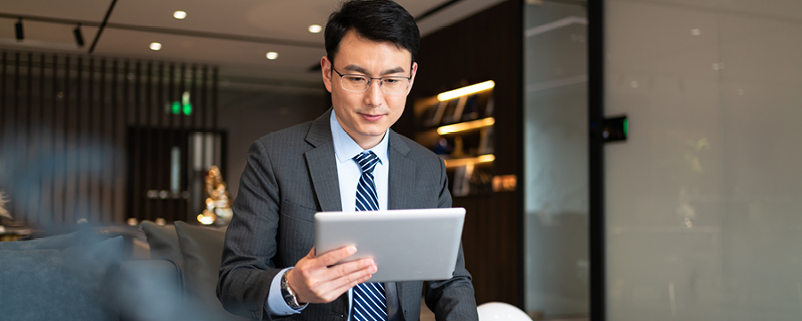 Portrait of confident businessman reviewing work on his tablet.